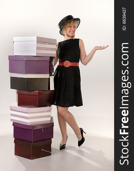 Cute happy blond girl in black dress showing off her stack of hat box purchases. Cute happy blond girl in black dress showing off her stack of hat box purchases