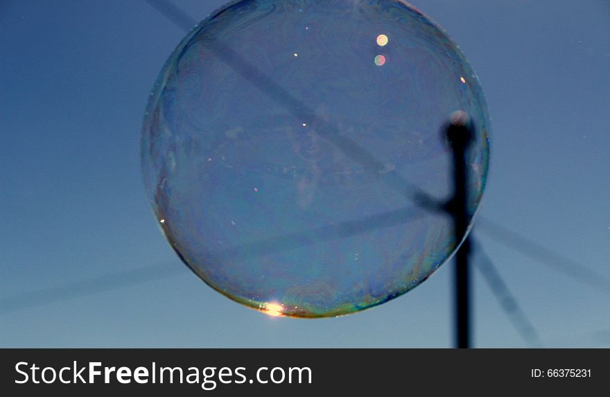 Shimmering bubble cluster with bokeh effect  floating past telephone wires. Shimmering bubble cluster with bokeh effect  floating past telephone wires