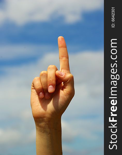 Hand pointing with index finger against a sky background