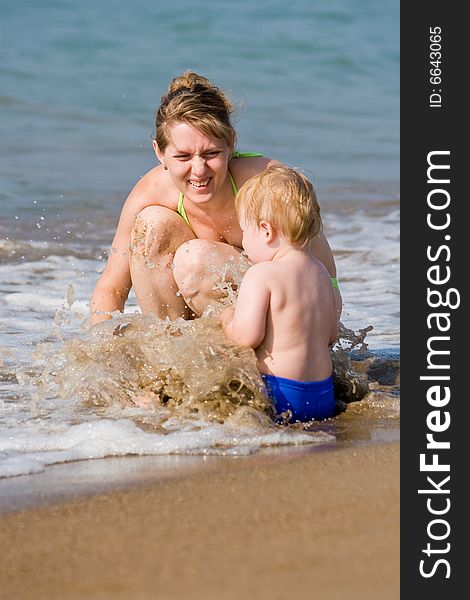 Mum with the child sit in waves of a surf