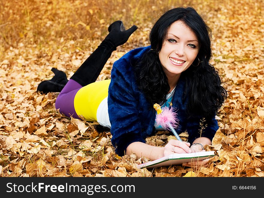 Pretty brunette girl in the park with a pen and a note-book. Pretty brunette girl in the park with a pen and a note-book