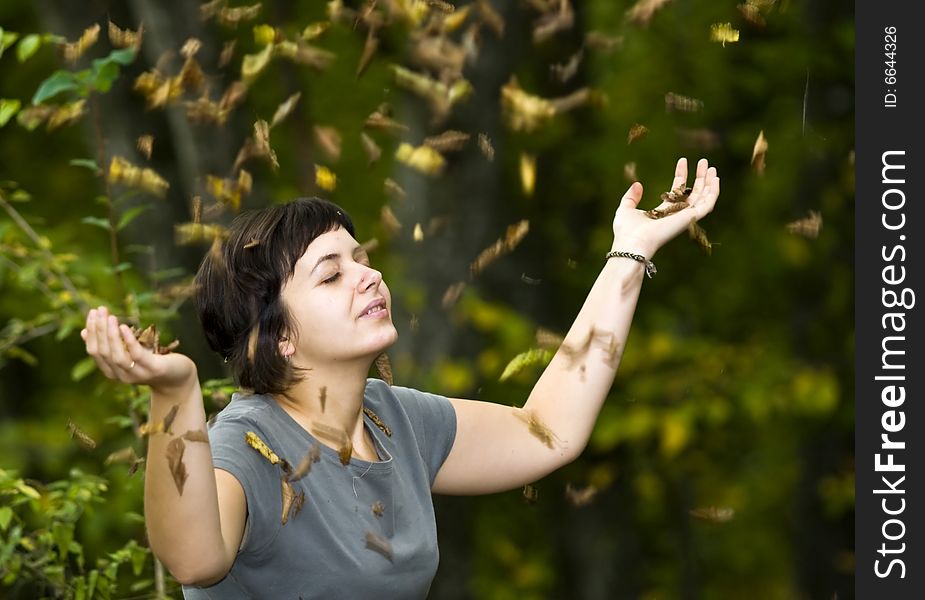 Girl relaxing in autumn park with falling leaves