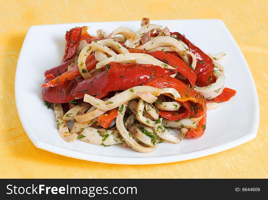 Squids with pepper on a plate of white, yellow background