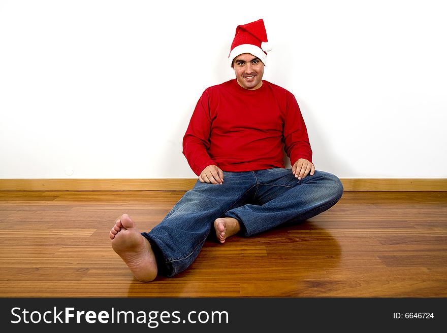 Young man with santa claus hat sitting in the floor