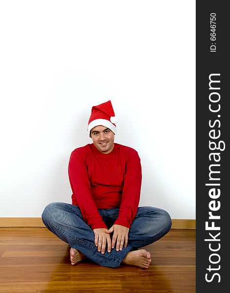 Young man with santa claus hat sitting in the floor