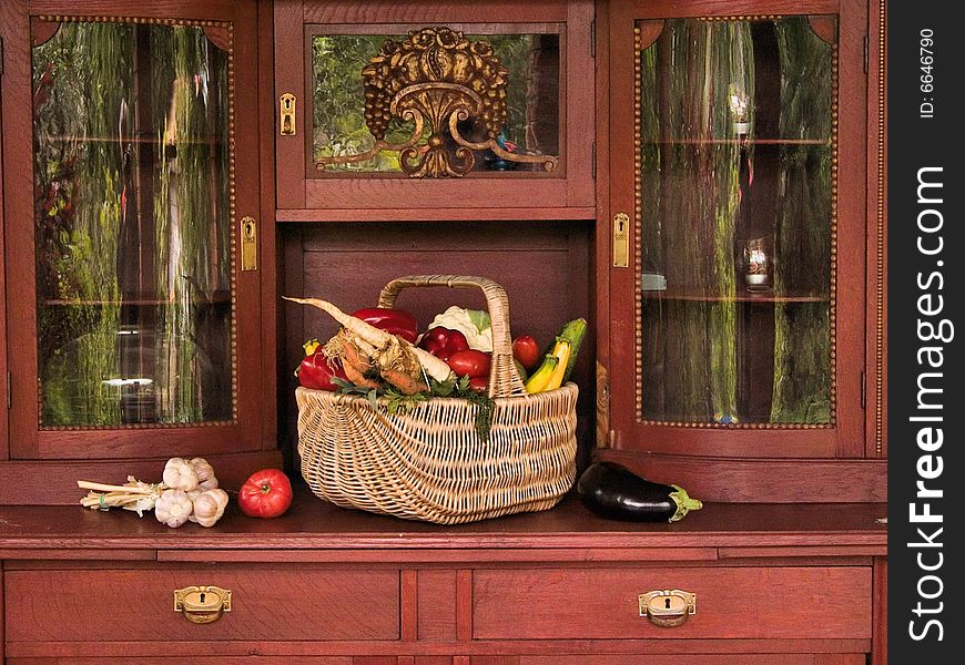 Basket full of vegetables on old cupboard.
