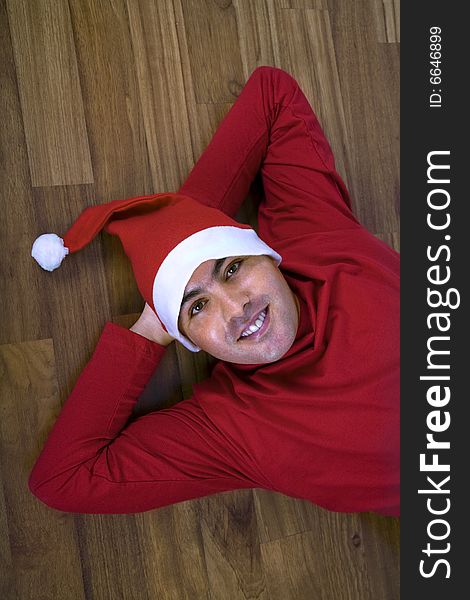 Smiling young man with santa claus hat lying in the floor