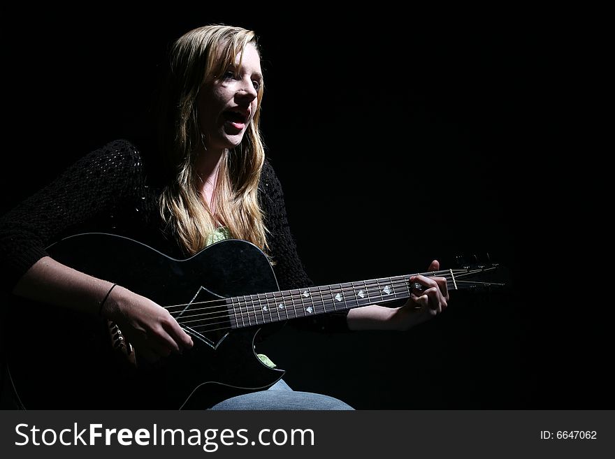 Moody picture of beautiful woman playing guitar and singing