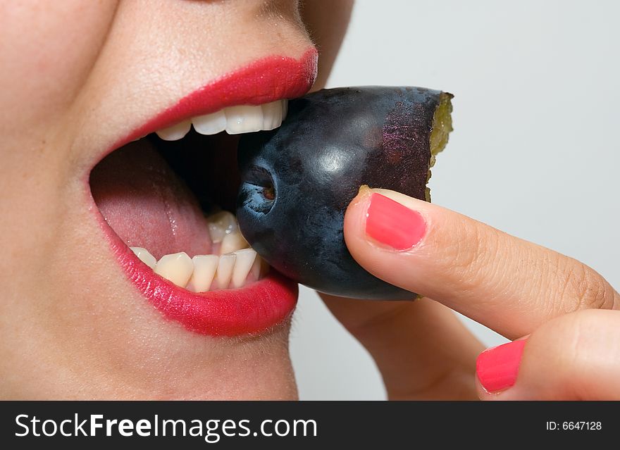 Attractive girl with red lipstick, eating a plum. Attractive girl with red lipstick, eating a plum