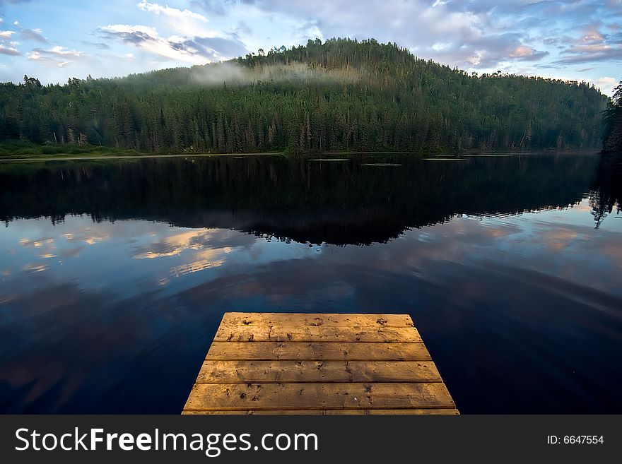 Peaceful fishing lake with deck and a mountain in the background. Peaceful fishing lake with deck and a mountain in the background