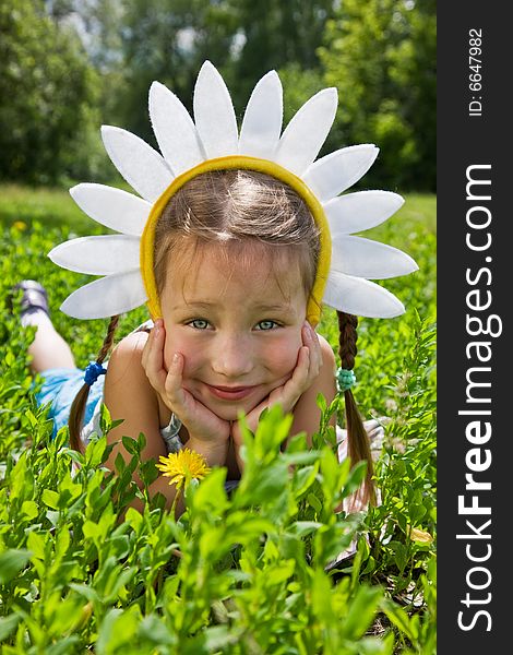 Portrait of little girl in camomile hat on green grass in a sunny day. Portrait of little girl in camomile hat on green grass in a sunny day