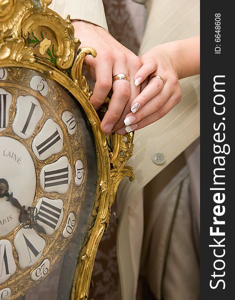 Married couple hands on old clock