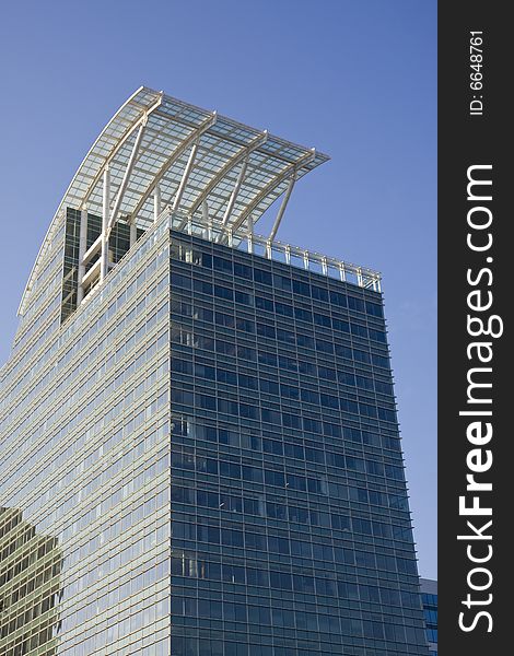 A blue office tower with a curved white roof. A blue office tower with a curved white roof