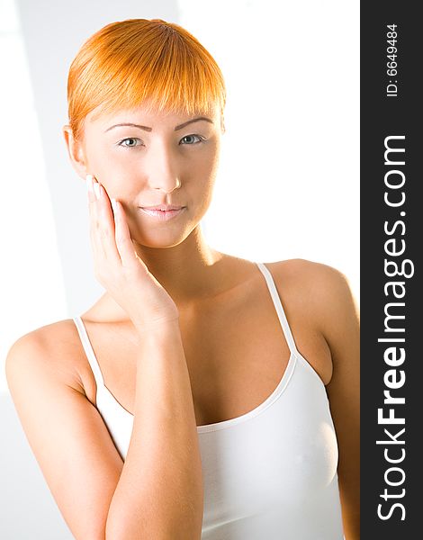 Young red-haired woman touching her skin on face. She's  looking at camera. Front view. Young red-haired woman touching her skin on face. She's  looking at camera. Front view.