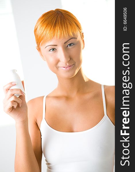 Young beautiful woman holding the container with cream. She's smiling and looking at camera. Front view. Young beautiful woman holding the container with cream. She's smiling and looking at camera. Front view.