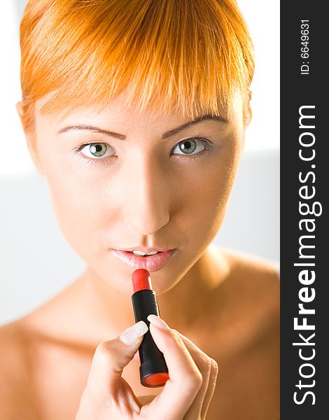 Beautiful woman applying red lipstick. She's looking at camera. Closeup on face. Front view. Beautiful woman applying red lipstick. She's looking at camera. Closeup on face. Front view.