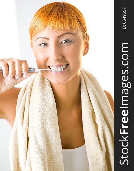 Young beauty woman with toothbrush and towel. She's brushing her teeth and looking at camera. Front view. Young beauty woman with toothbrush and towel. She's brushing her teeth and looking at camera. Front view.