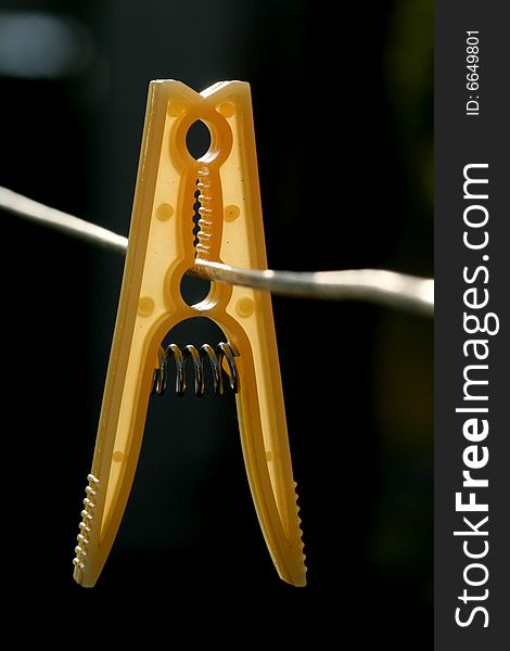 Yellow clothes-peg on rope, black background