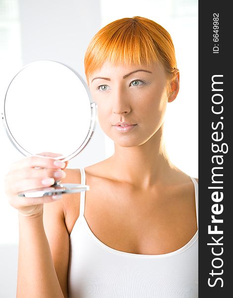 Young woman looking in mirror. Front view. Young woman looking in mirror. Front view.