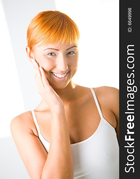 Young red-haired woman touching her skin on face. She's smiling and looking at camera. Front view. Young red-haired woman touching her skin on face. She's smiling and looking at camera. Front view.