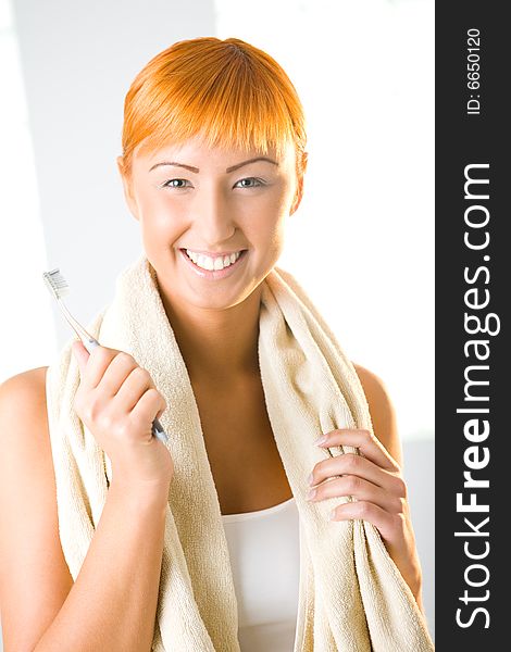 Young beauty woman with toothbrush and towel. She's smiling and looking at camera. Front view. Young beauty woman with toothbrush and towel. She's smiling and looking at camera. Front view.