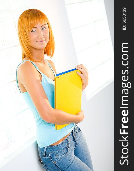 Young sexy woman standing beside window with notepad. She's smiling and looking at camera. Young sexy woman standing beside window with notepad. She's smiling and looking at camera.