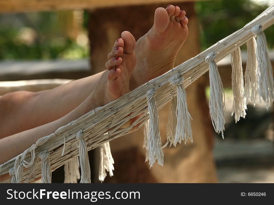Female feet on hammock at the caribbean beach