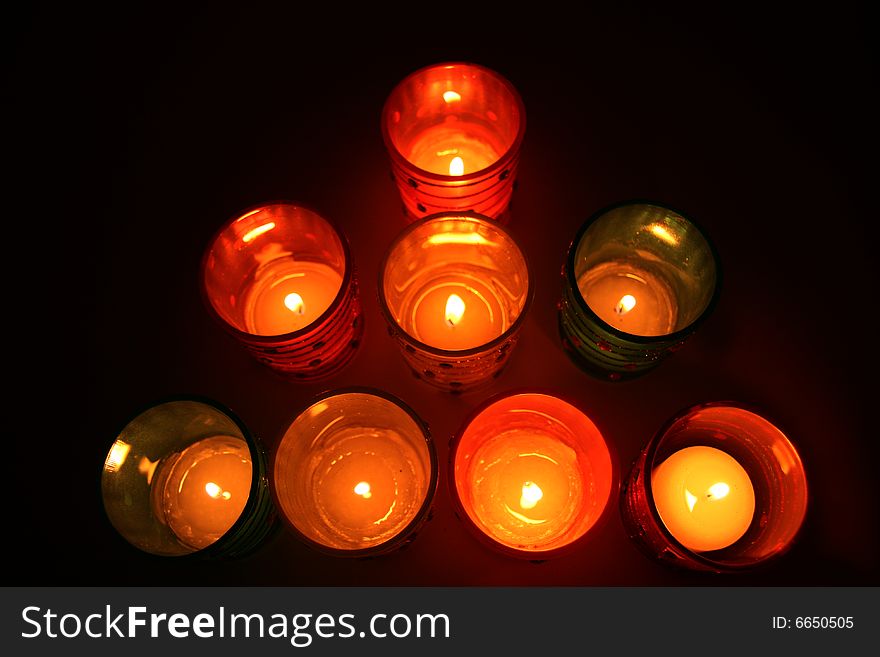 Glass votive candles lit up in dark room