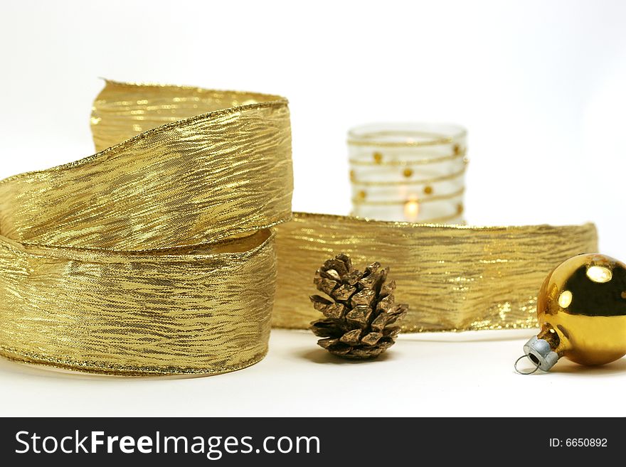 Gold ribbon, pine cone, ornament  and votive on white background. Gold ribbon, pine cone, ornament  and votive on white background