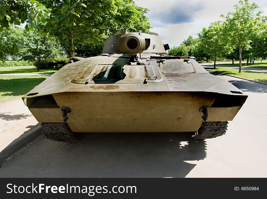 A front view of an old tank parked in a park. A front view of an old tank parked in a park