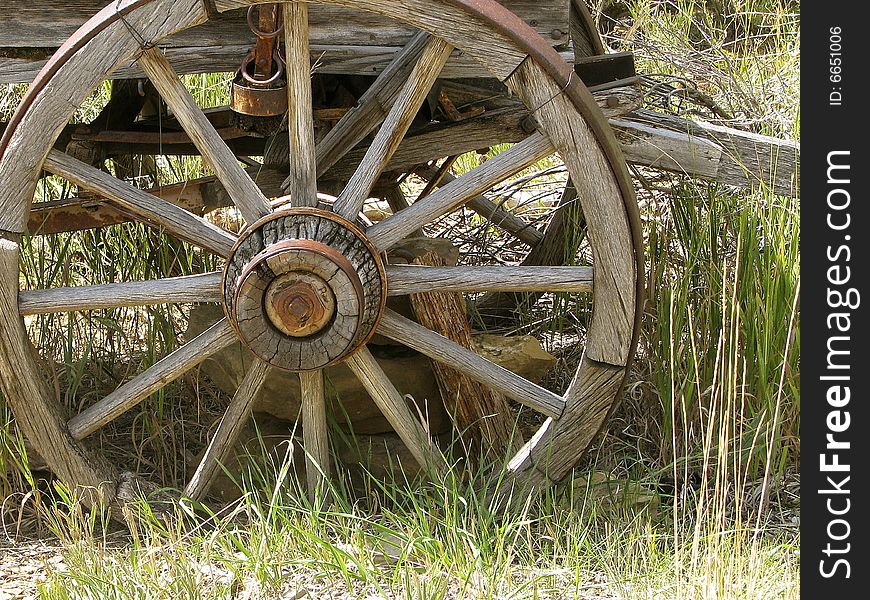 Really old worn wagon wheel in grass. Really old worn wagon wheel in grass