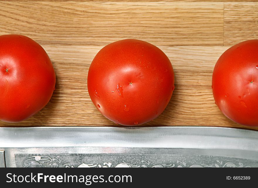 Sharp knife and tomato on a bamboo chopping board