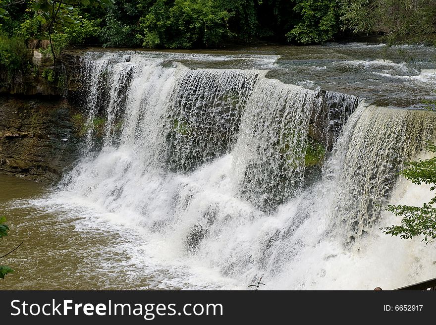 Water falling quickly over rocks surrounded by tons of green trees and plants. Water falling quickly over rocks surrounded by tons of green trees and plants