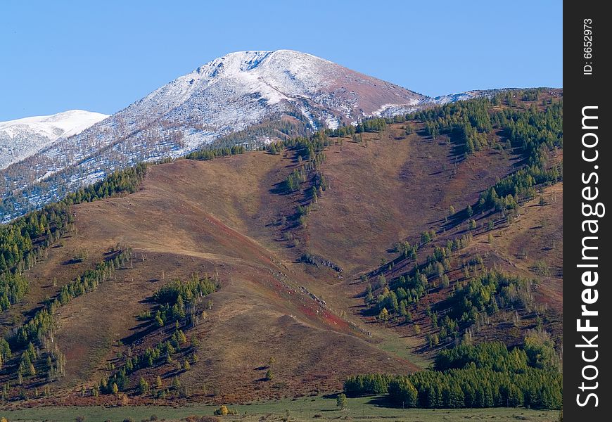 Snow top on background of the mountains by autumn