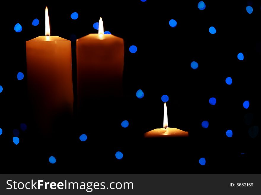 Three burning candles with blue lights in background, dark shadows. Three burning candles with blue lights in background, dark shadows