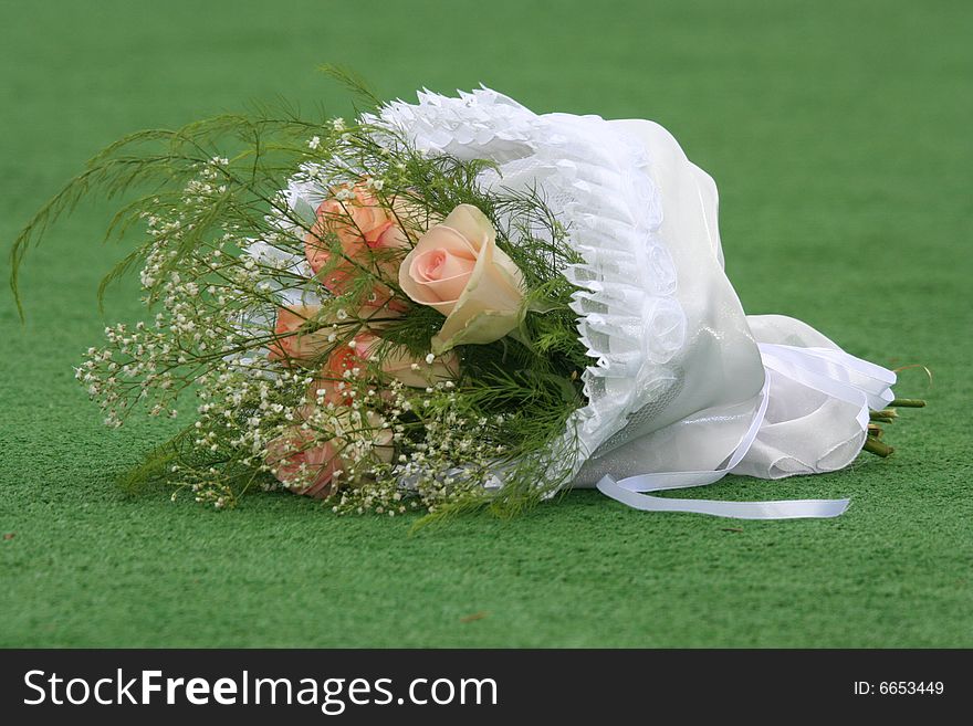 The beautiful wedding bouquet of roses lays on a grass.