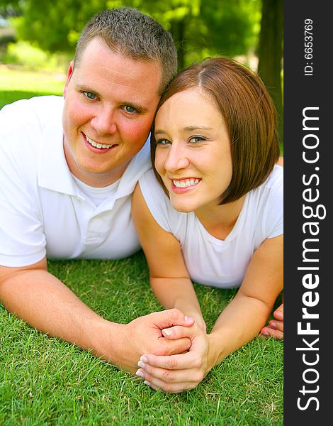 Happy caucasian couple laying on grass and holding hand with smile. concept for happiness and family. Happy caucasian couple laying on grass and holding hand with smile. concept for happiness and family