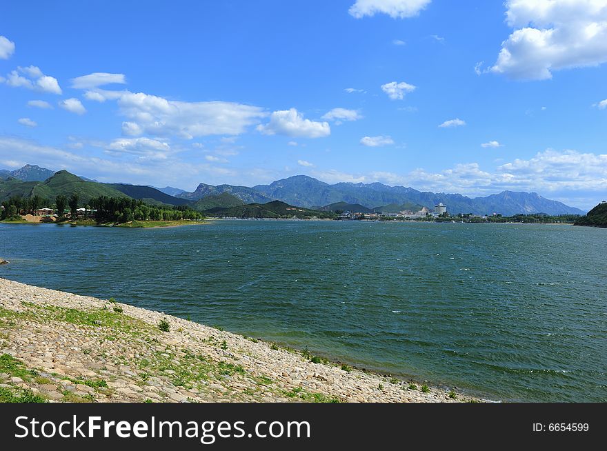 View of reservoir and mountains, blue sky and white clouds