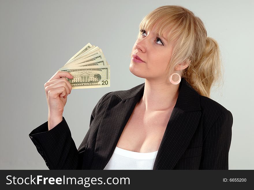 Woman fans herself with American currency on grey background