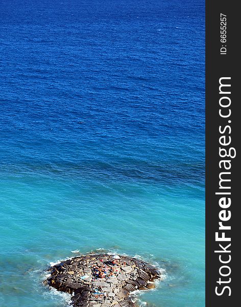 A mole of rocks with bathers and blue sea. A mole of rocks with bathers and blue sea