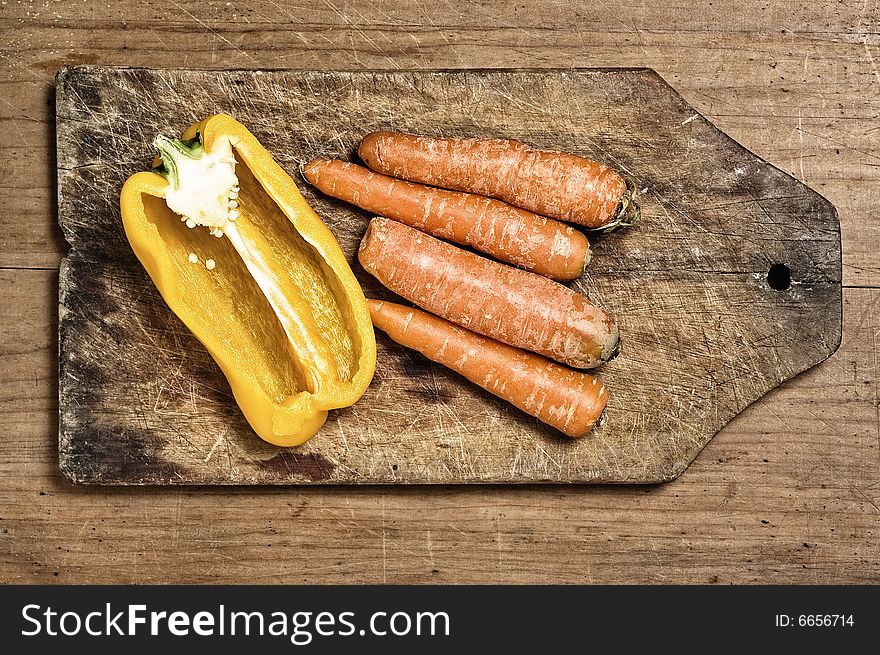 Yellow bell pepper and carrots on a wooden cutting table. Yellow bell pepper and carrots on a wooden cutting table.