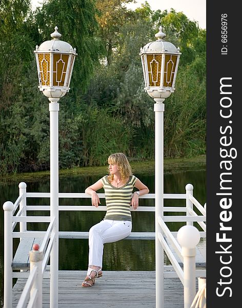 The girl sits on a pier and looks afar. The girl sits on a pier and looks afar