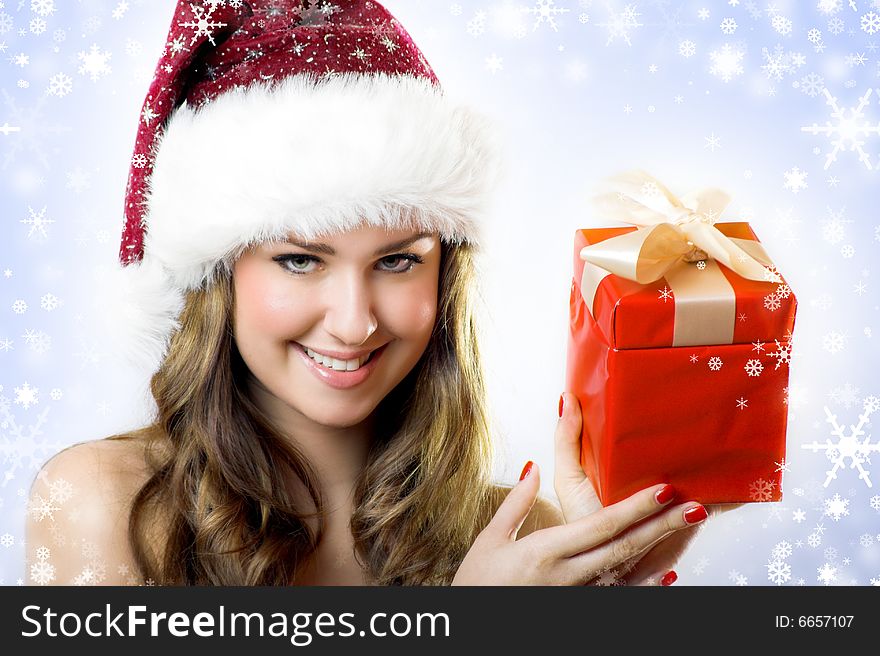 Winter portrait of a beautiful young woman with a cap  and a gift and snowflakes. Winter portrait of a beautiful young woman with a cap  and a gift and snowflakes