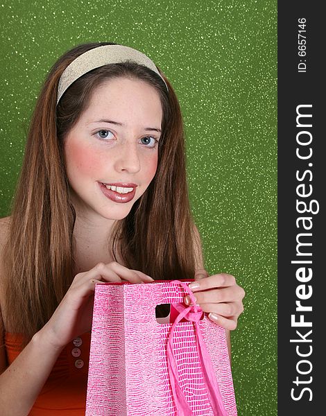 Brunette teenager on a green background opening a gift. Brunette teenager on a green background opening a gift