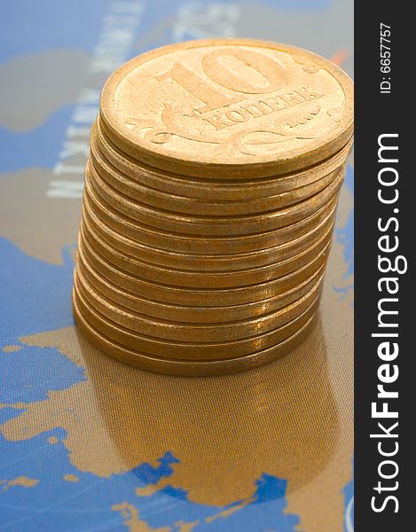 Stack of shiny coins over world map on plastic card. Stack of shiny coins over world map on plastic card