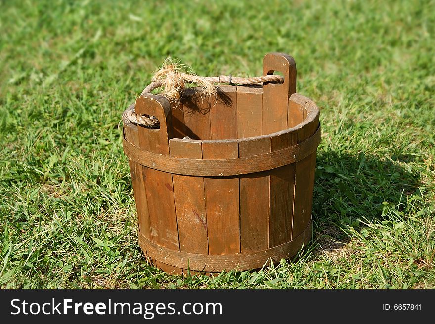 An old wooden bucket on grass. Buckets like this were commonly used to bring up water from a well.