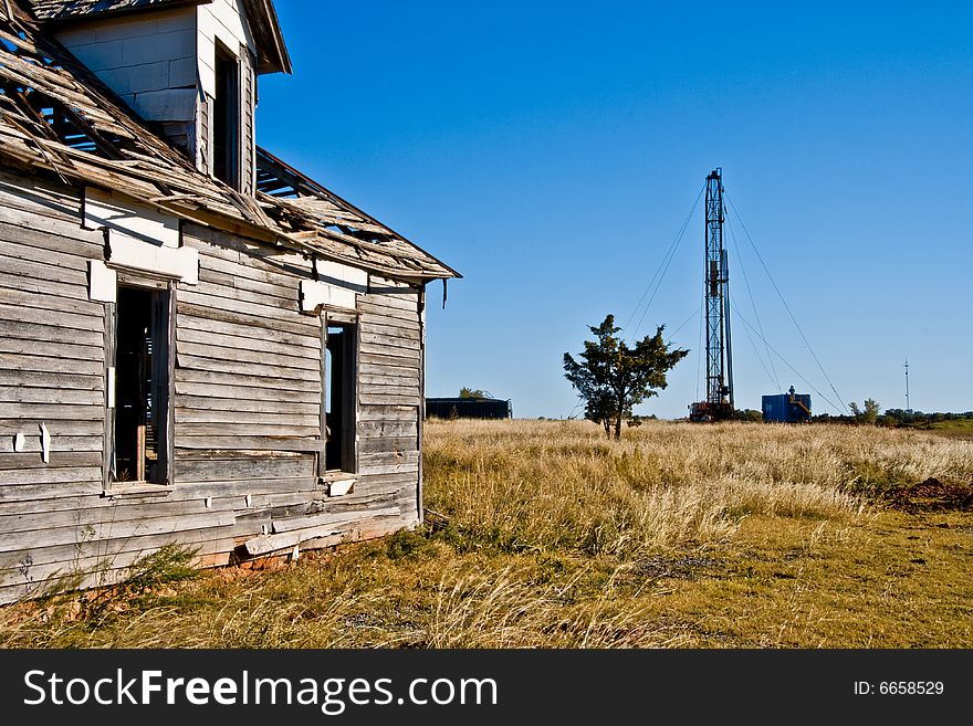 Abandoned house on the left and a drilling rig drilling for oil on the right with a cedar tree between the two. Legend has it that a cedar tree stands between life and death. Abandoned house on the left and a drilling rig drilling for oil on the right with a cedar tree between the two. Legend has it that a cedar tree stands between life and death.