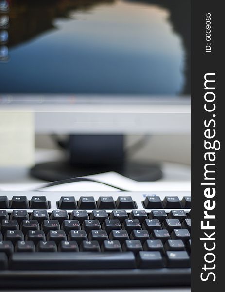 Shallow depth of field on a computer keyboard. On the background can be seen a part of the desktop LCD monitor. The focus is on the keyboard buttons.