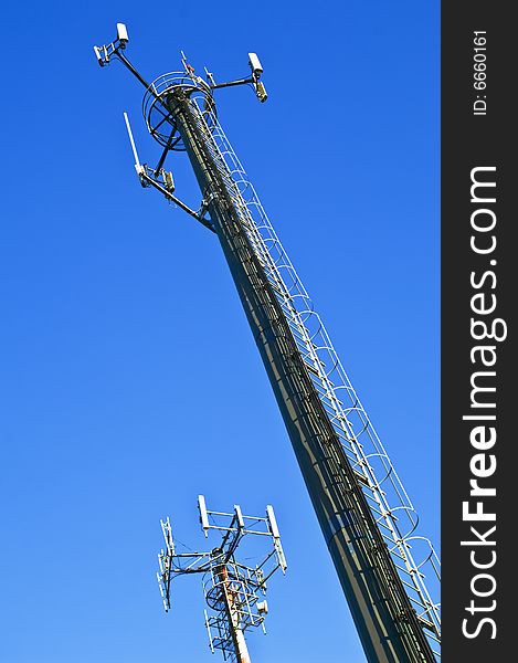 Two telecommunication antennas against a clear blue sky