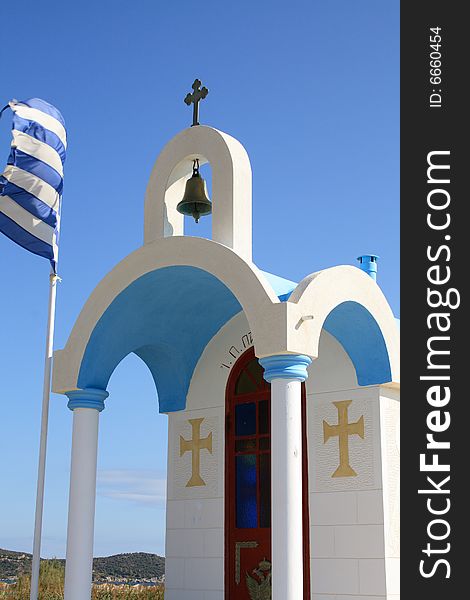 White little chapel in Greece with Greek flag